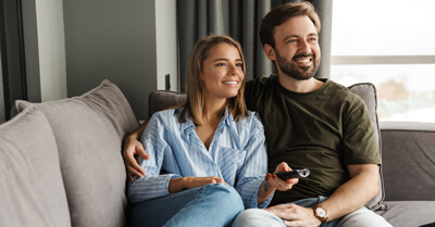 Young couple on sofa watching TV